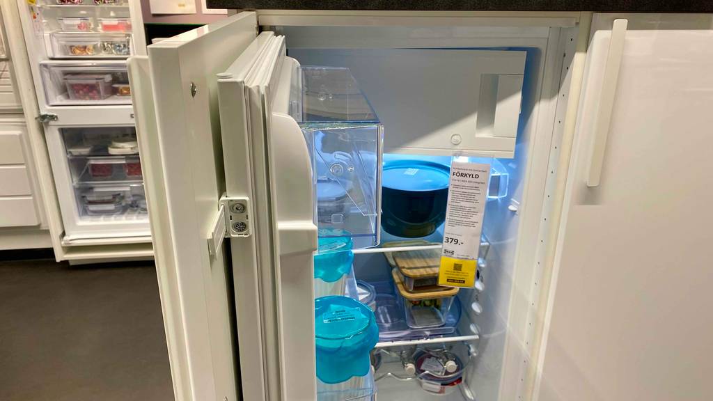 Ein Einbaukühlschrank-mit-Gefrierfach im Test: die geöffnete Türe eines Einbaukühlschranks von der Seite ersichtlich mit Blick in den Kühlschrank.