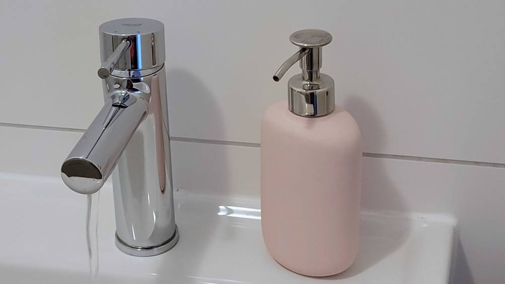 Ein getesteter Seifenspender steht auf einem Waschbecken neben einem Wasserhahn.