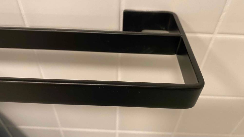 Detailaufnahme eines schwarzer Wand-Handtuchhalters im Test auf beigefarbener Fliesenwand.