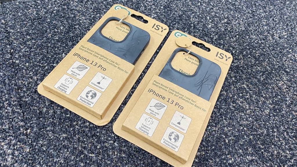 iPhone-13-pro-Hülle getestet: zwei Handyhüllen in Papierverpackung liegen auf einem dunklen Stoff.