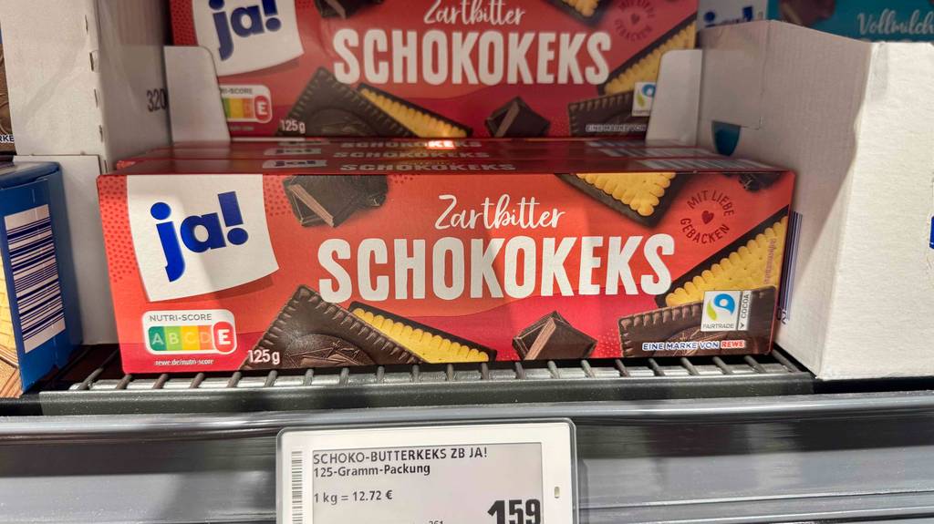 Mehrere Packungen der getesteten Schokokekse sind in einem Regal einsortiert, wobei das Preisschild ersichtlich ist.