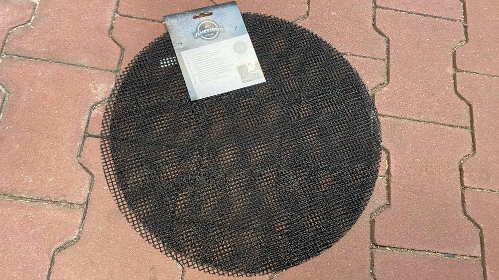 Grillmatten-Test: Eine schwarze Grillmatte liegend auf einem Boden.