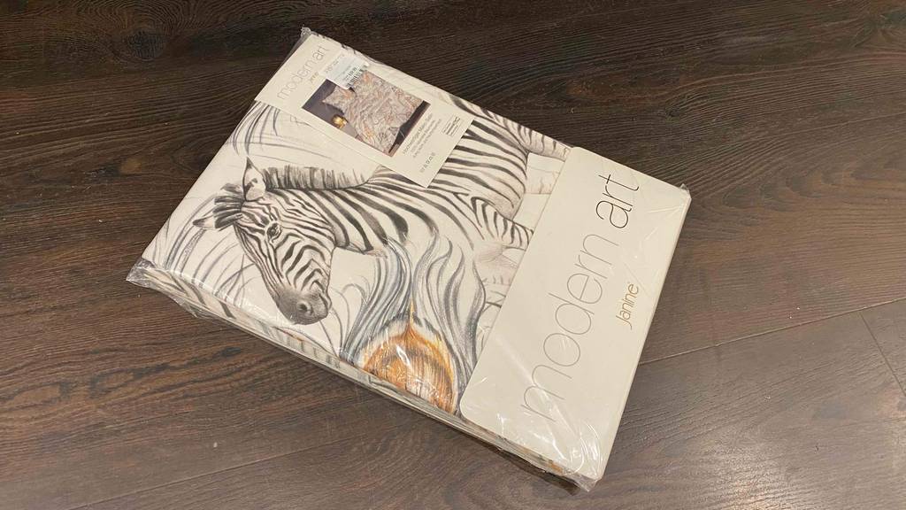 Mako-Satin-Bettwäsche getestet: Auf einem Holzboden liegt eine verpackte Mako-Satin-Bettwäsche.