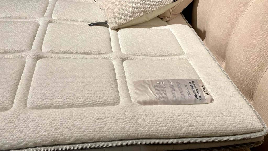 Kaltschaum-Topper-Test: ein Kaltschaum-Topper auf einem Bett mit einem Etikett darauf.