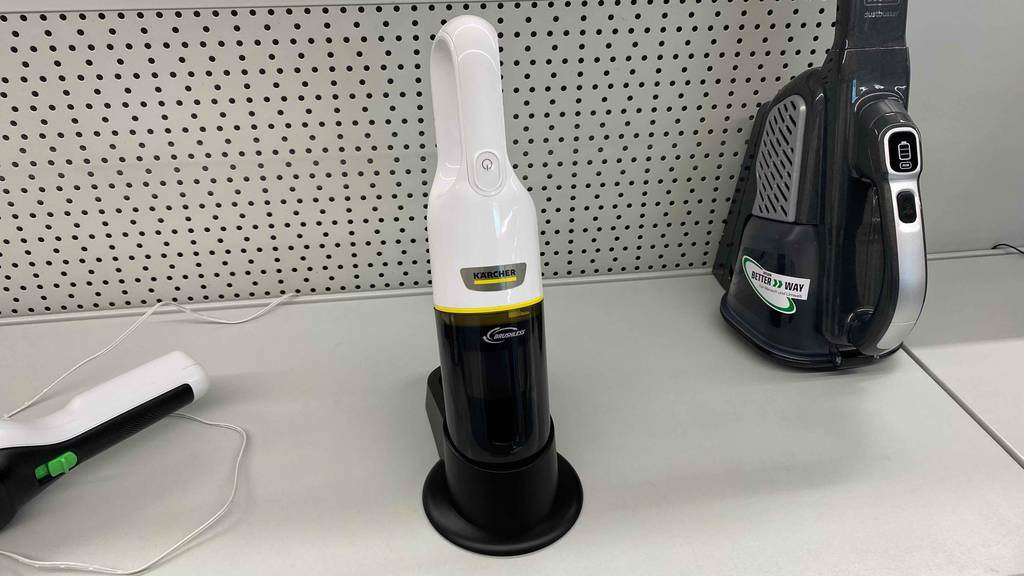 Ein getesteter Handstaubsauger mit Kabel neben anderen Produkten im Regal.