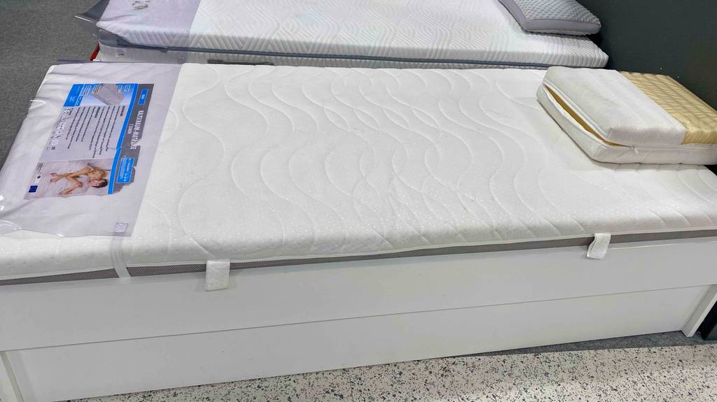 Im Test: Eine Kaltschaummatratze 90 x 200 cm von der Seite in eine Bettgestell in einer Austellung.