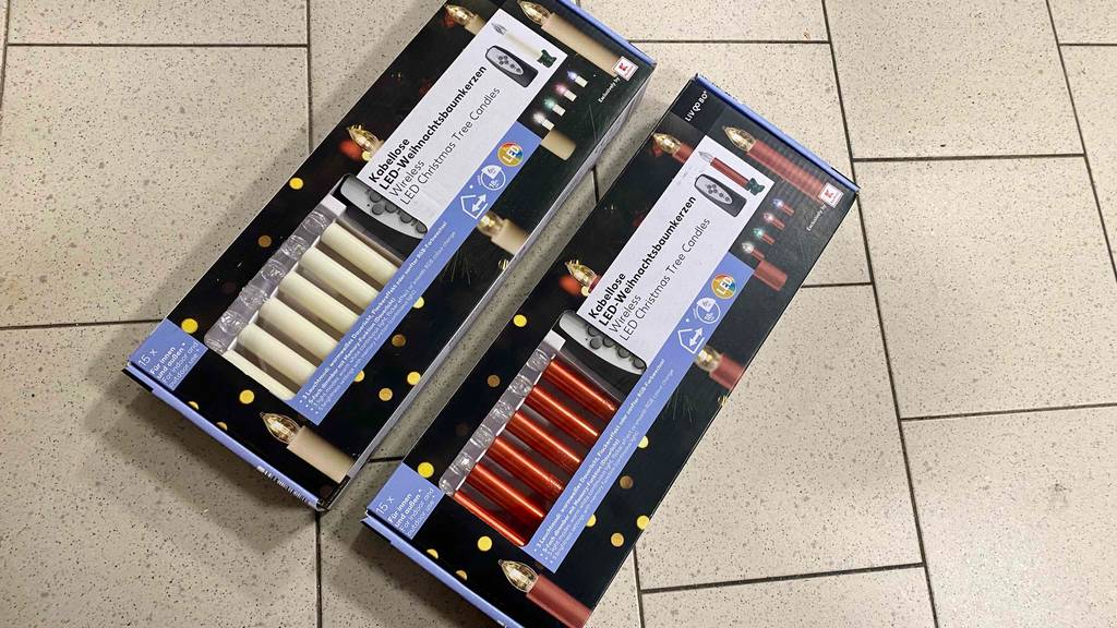 Zwei Packungen der getesteten kabellosen Christbaumkerzen auf einer Fließenoberfläche.