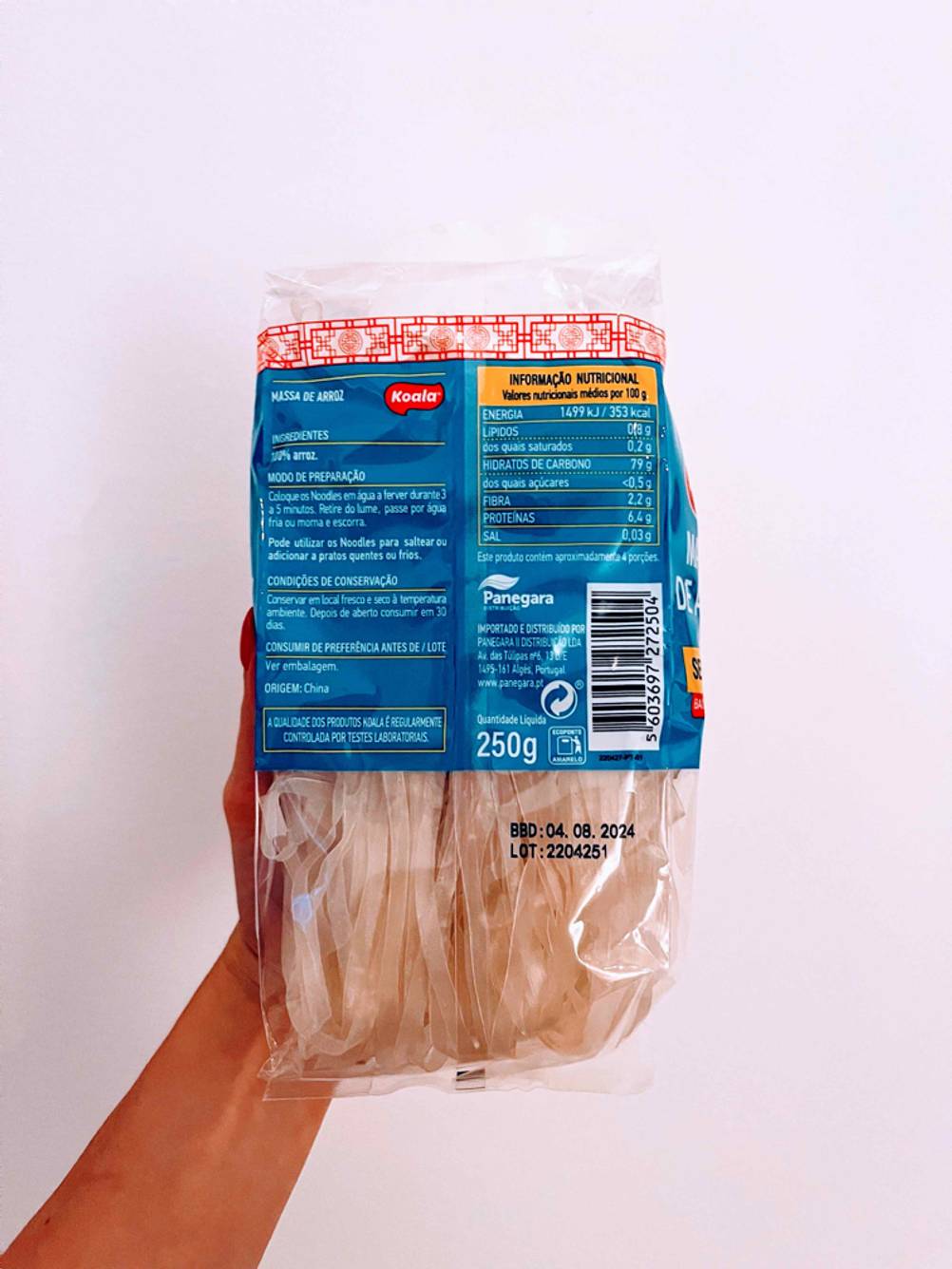 Eine Hand hält die Rückseite einer Packung getesteter Konjak-Nudeln vor eine helle Wand.