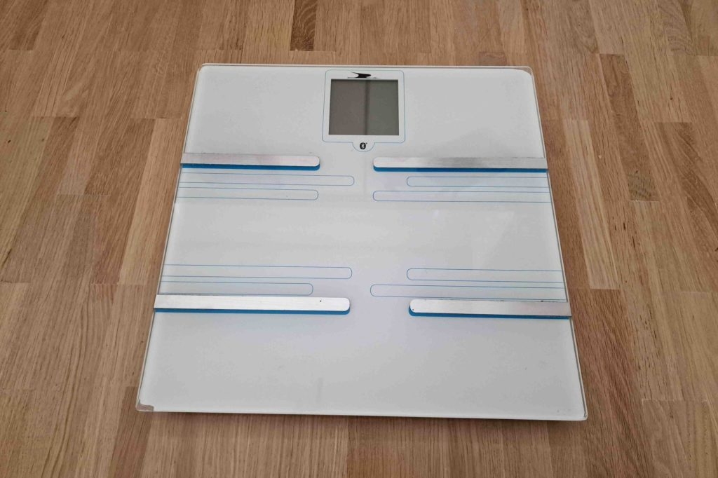 Auf einem Holzboden steht eine getestete Körperfettwaage.