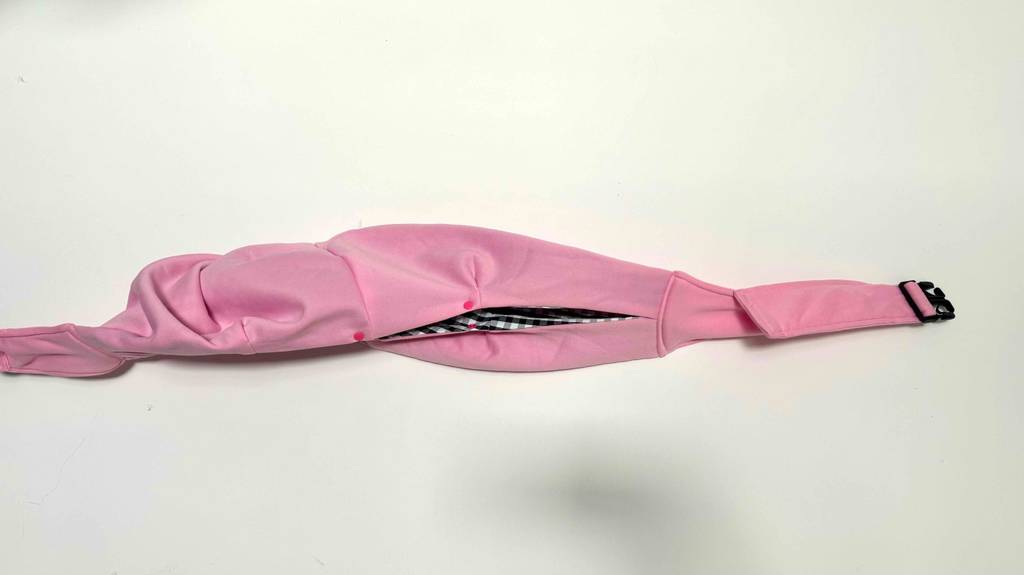 Das getestete Hundetragetuch in der Farbe Rosa liegt ausgebreitet auf einer weißen Fläche.