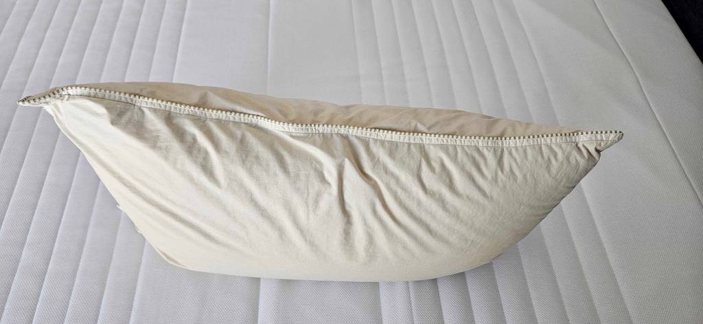 Kopfkissen-40x60 im Test: ein Kopfkissen ohne Bezug ist uf einem Bett platziert.