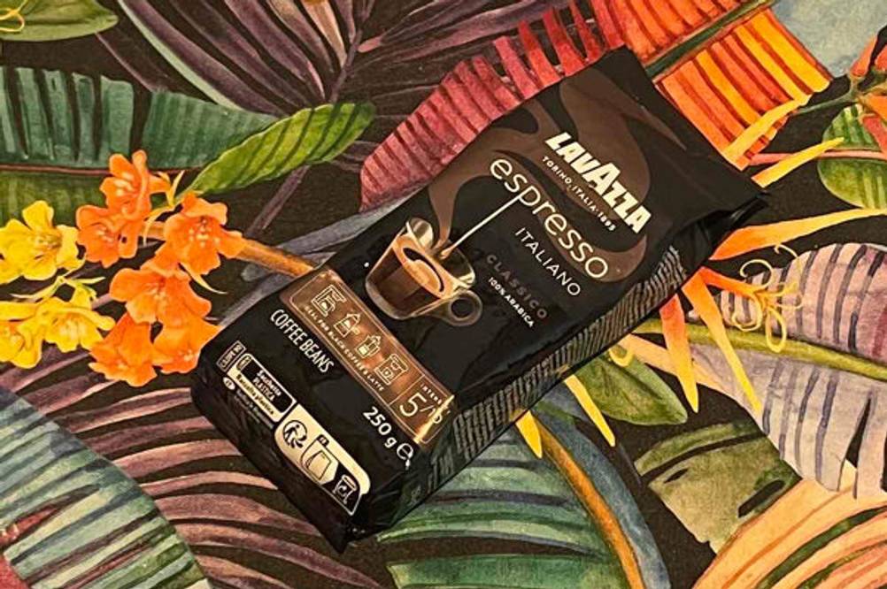 Eine Packung der getesteten Lavazza-Kaffeebohnen liegt auf einer bunten Tischdecke.