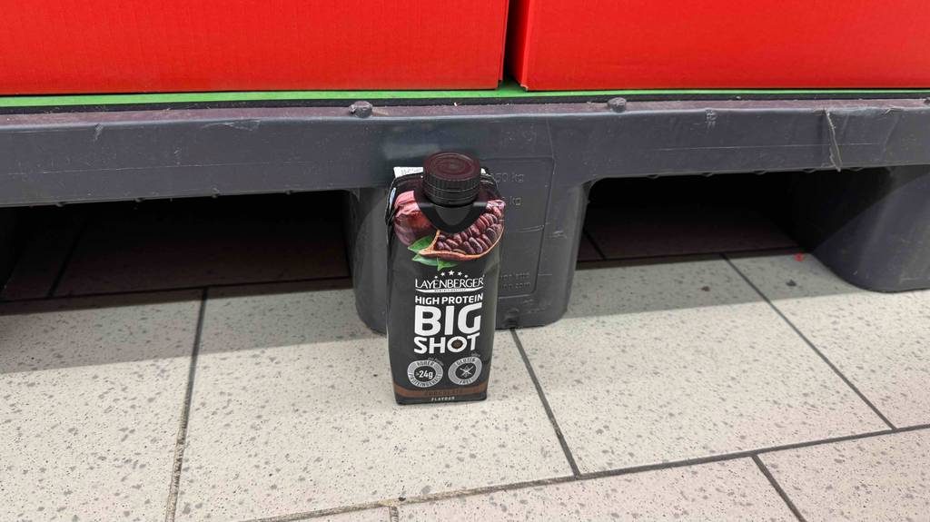 Ein getesteter Eiweißdrink steht auf einem Boden.