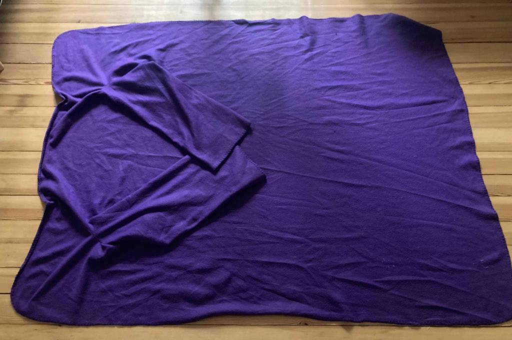Decke mit Ärmeln-Test: violette Decke mit Ärmeln ausgebreitet auf einem Boden liegend.