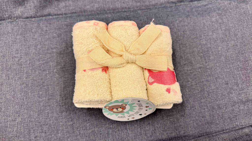 Getesteter Waschlappen für Babys: Drei eingerollte Waschlappen für Babys sind mit einer Schlaufe zusammengebunden.