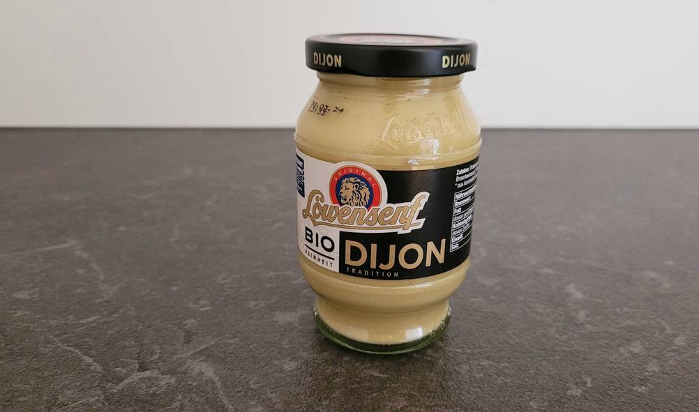 Dijon Senf im Test: Ein Glas Senf steht auf einer dunklen Arbeitsplatte