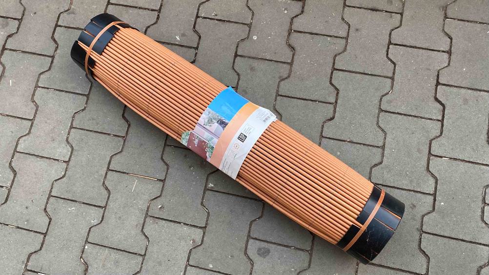Balkon-Sichtschutz im Tes: Balkon-Sichtschutz aufgerollt mit Papieretikett auf einem Boden liegend.