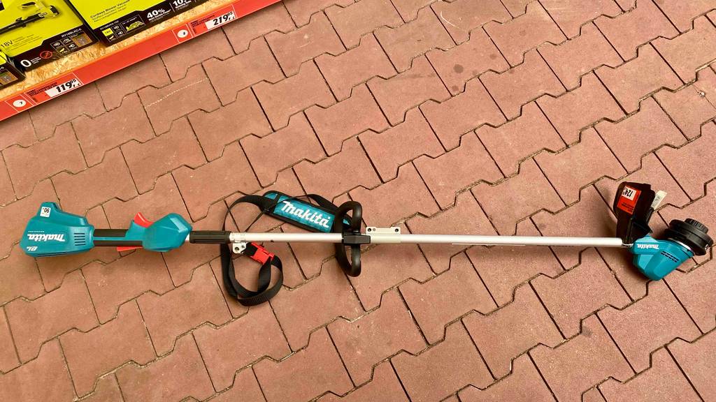 Ein getesteter Makita-Rasentrimmer liegt auf einem Boden.