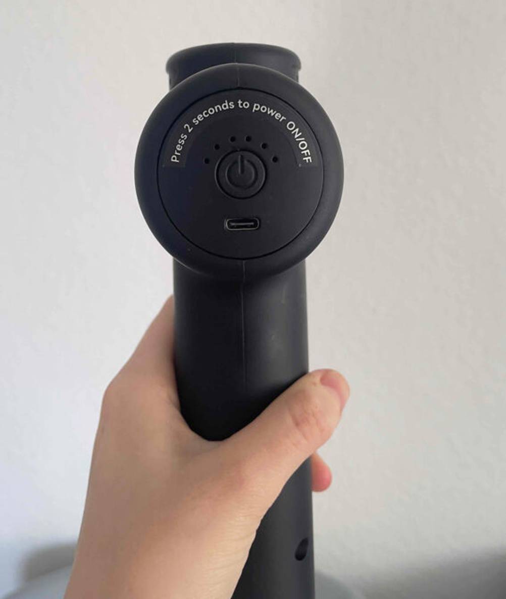Mini-Massagepistolen im Test: Ansicht auf den Einschaltknopf des schwarzen Modells.