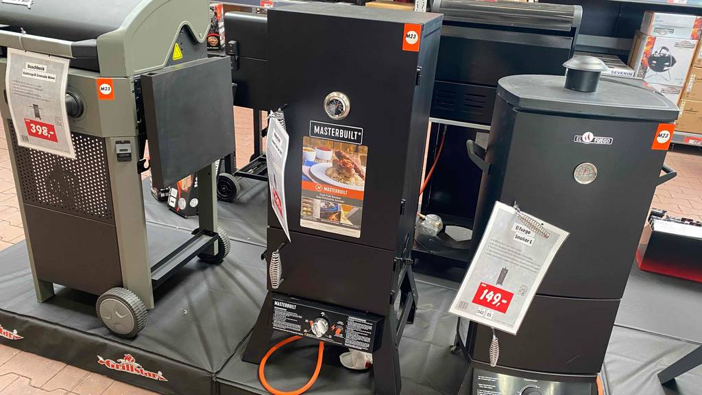 Gas-Smoker im Test: ein Gas-Smoker von Masterbuilt von vorn ersichtlich, neben anderen Modellen stehend.