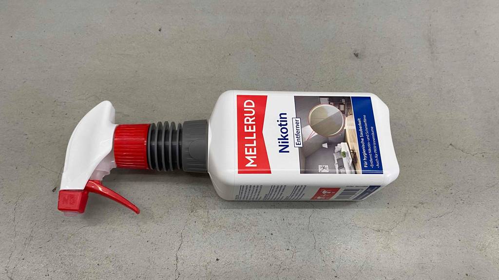 Liegender getesteter Mellerud-Nikotinreiniger in 500-ml-Sprühflasche auf grauem Untergrund.