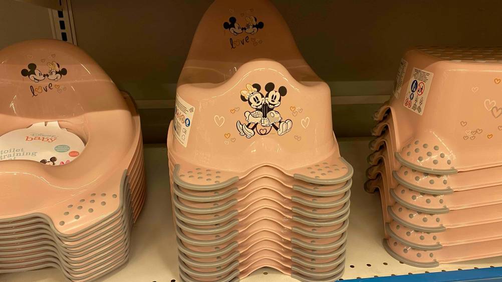 Töpfchen im Test: mehrere Töpfchen mit Minnie- und Mickey-Mouse darauf in einem Regal platziert, neben Hockern des gleichen Designs.