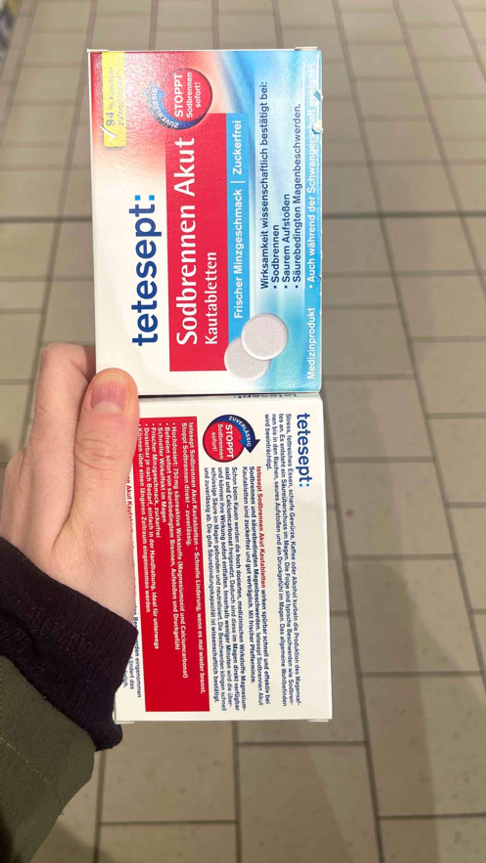 Mittel gegen Sodbrennen-Test: Die Verpackungen der Kautabletten werden in der Hand gehalten, wobei bei einer die Vorderseite und einer die Rückseite ersichtlich ist.
