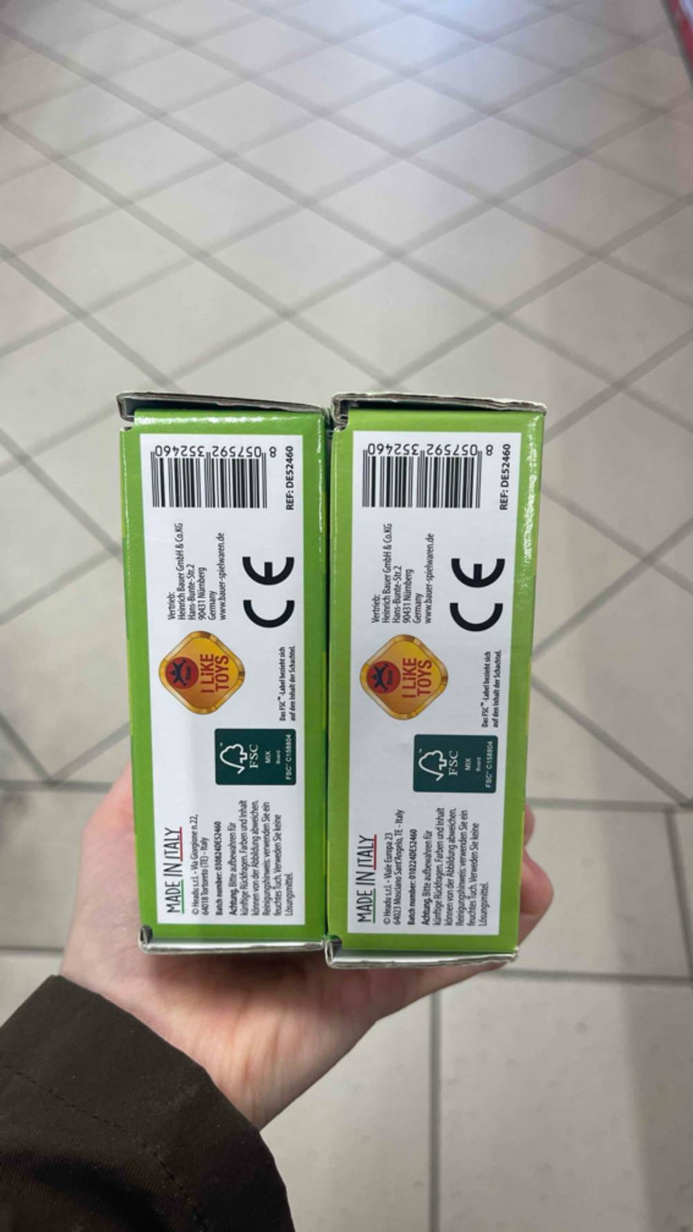 Die Unterseite der zwei Verpackungen des Montessori-Spielzeugs werden in der Hand gehalten.