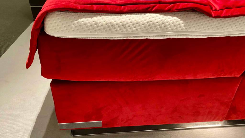 Boxspringbett-160x200 im Test: Nahaufnahme des roten Bettrahmens eines Boxspringbettes.
