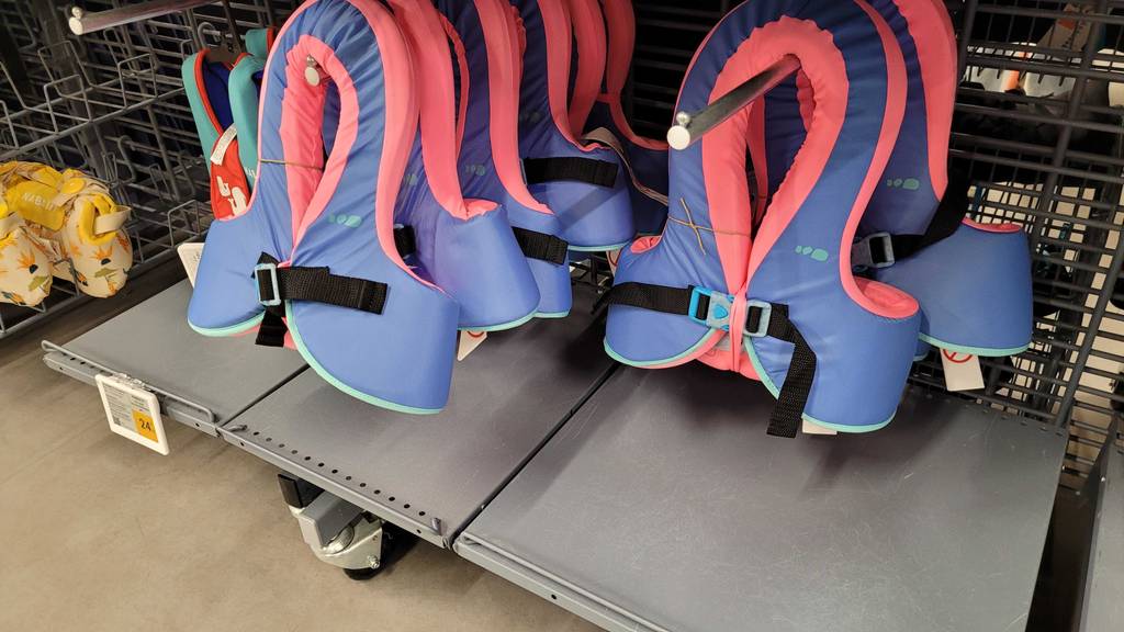 Mehrere getestete Schwimmwesten hängen in einem Regal, mit dem entsprechenden Preisschild ersichtlich.