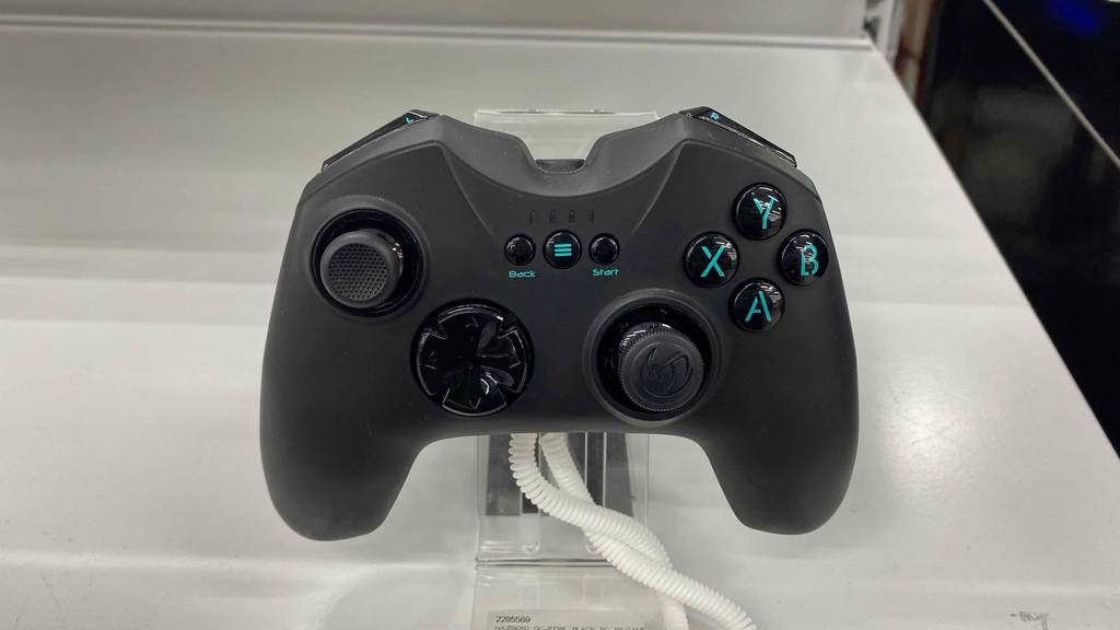 Ein getestetes Gamepad von nacon steht in einem Acylständer auf einer hellen Fläche.