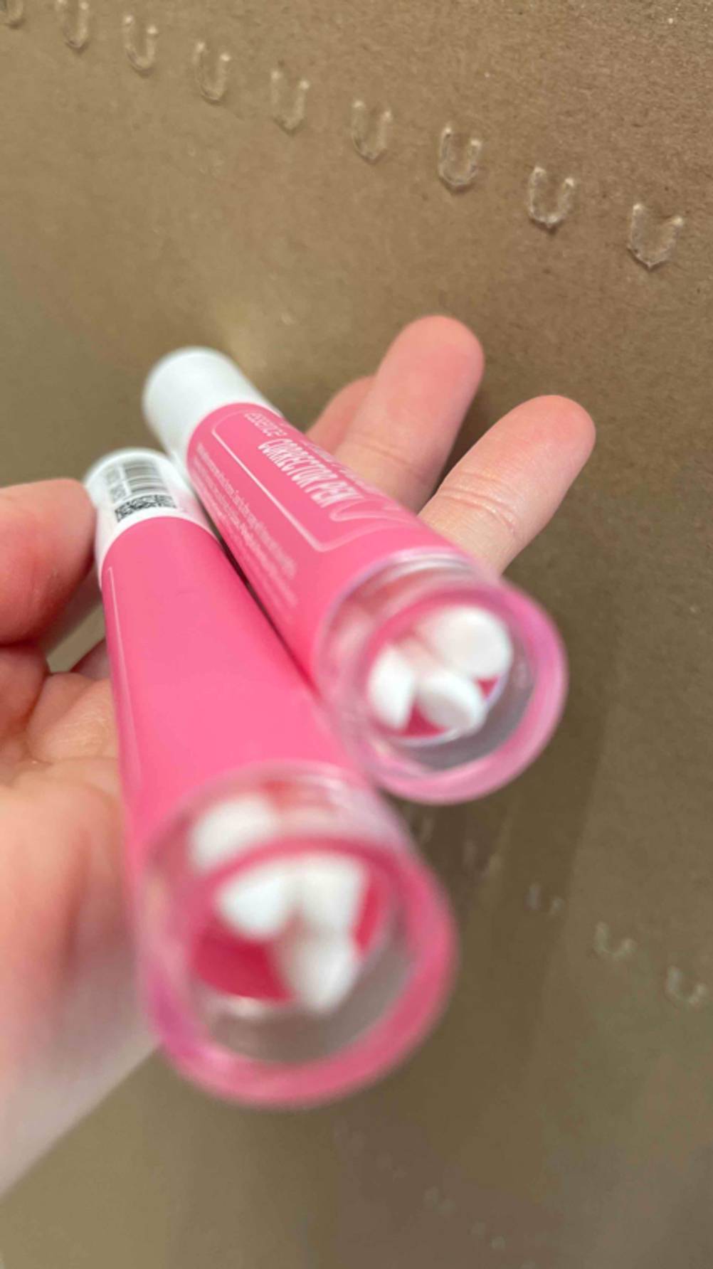 Zwei getestete Nagellack-Korrekturstifte werden in der Hand gehalten.