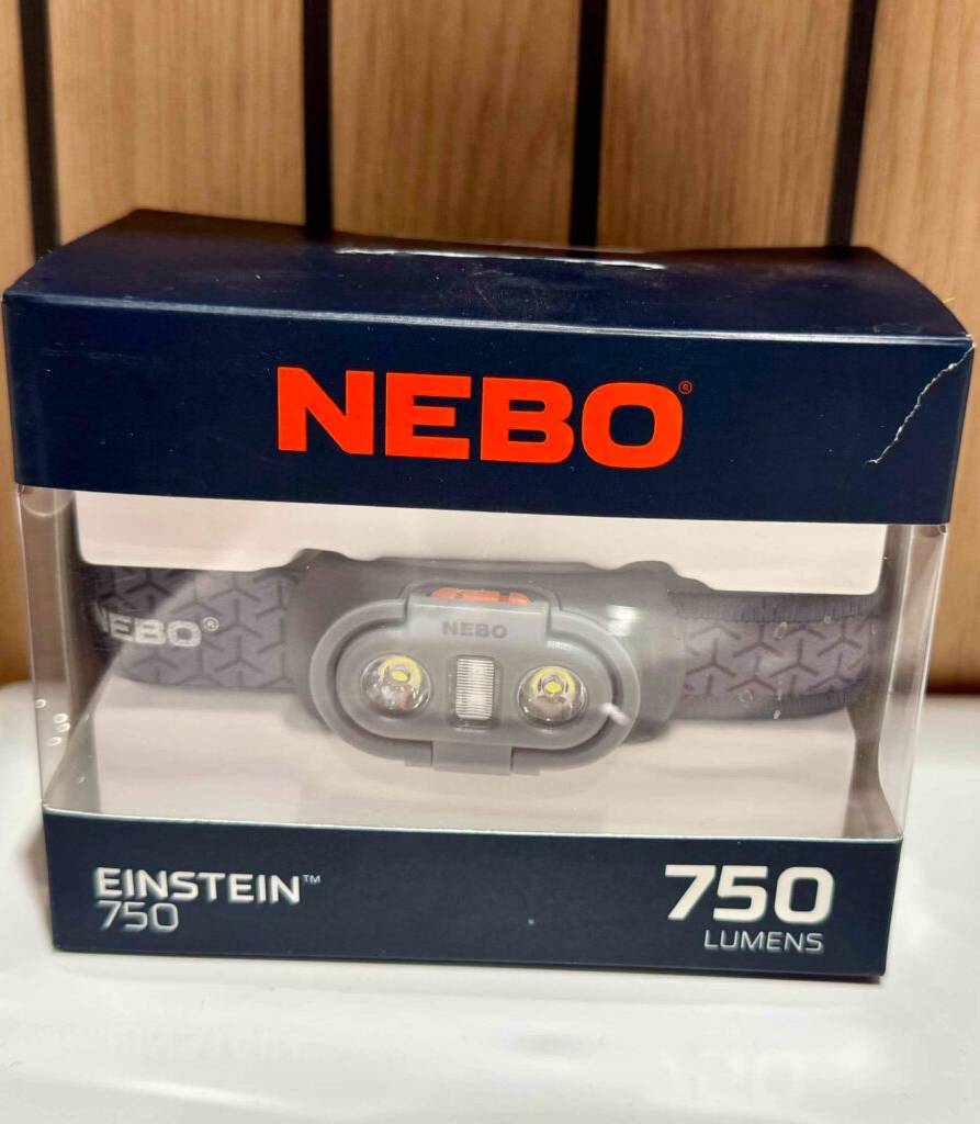 Akku-Stirnlampen-Test: Ein 750-Lumen-Modell der Marke NEBO steht eingepackt auf einer Holzfläche.