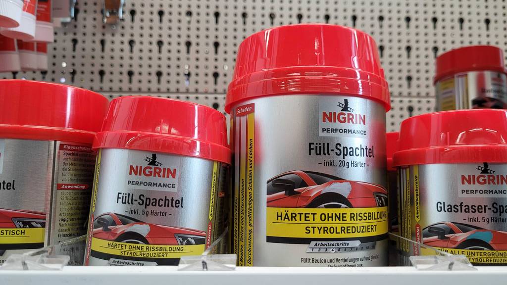 Mehrere Dosen in unterschiedlichen Größen der getesteten Spachtelmasse (Auto) in einem Regal.