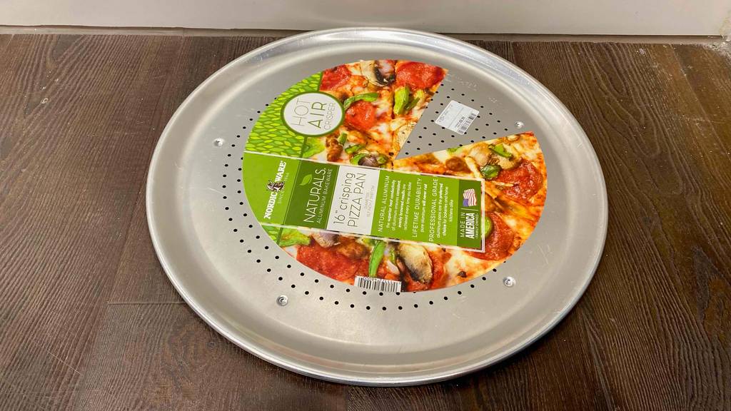 Pizzablech im Test: ein Pizzablech mit Papiereinlage darauf auf einem Boden liegend.
