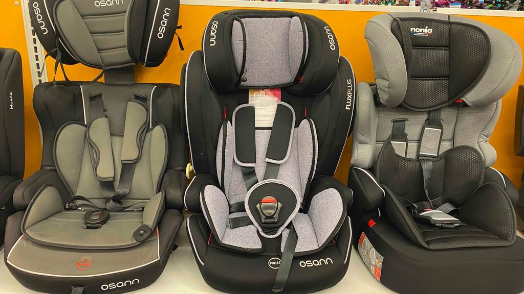 Ein getesteter Kindersitz 9–36 kg von vorne neben anderen Sitzen im Regal.