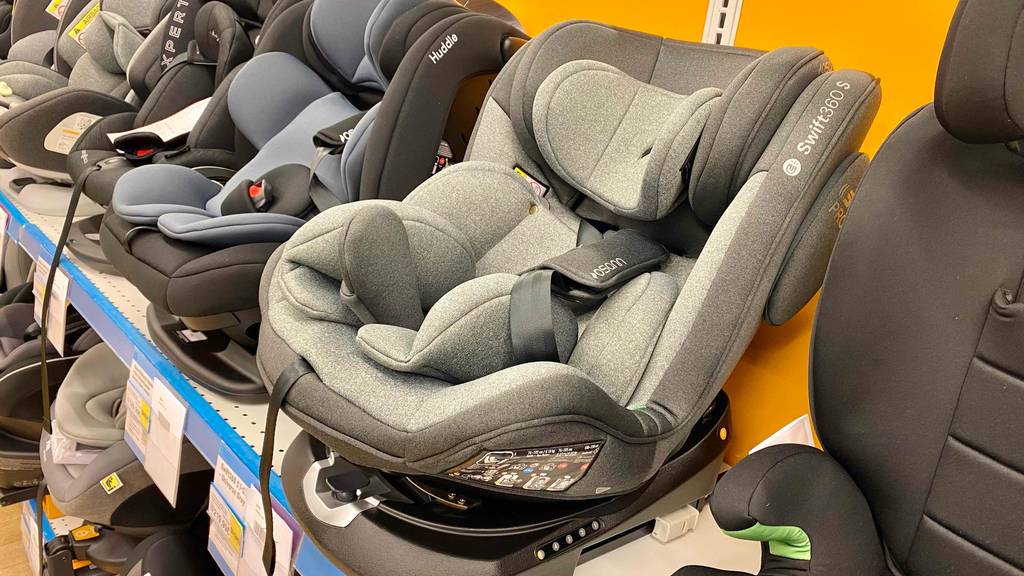 Ein getesteter drehbarer Kindersitz von schräg vorne neben anderen Sitzen in einem Regal.