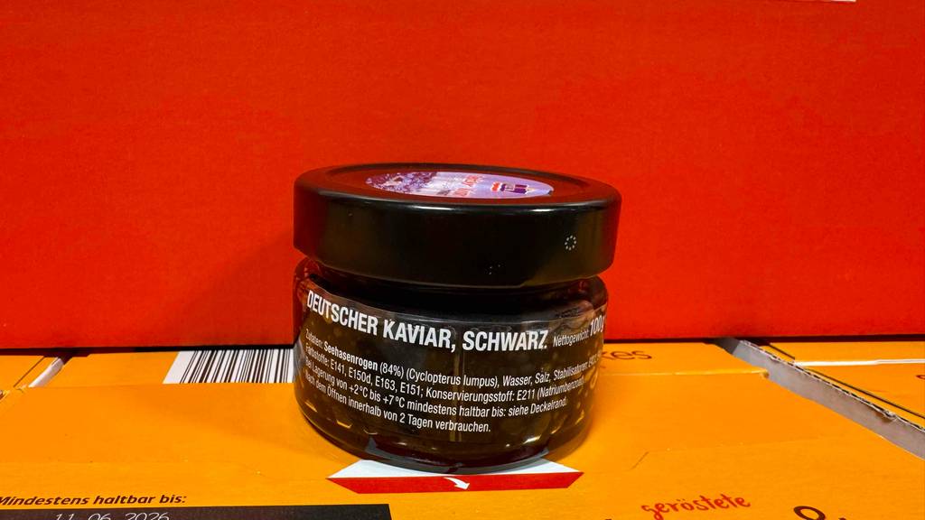 Kaviar im Test: Eine Dose mit schwarzem Kaviar aus Deutschlandsteht steht vor einer orangefarbenen Fläche.
