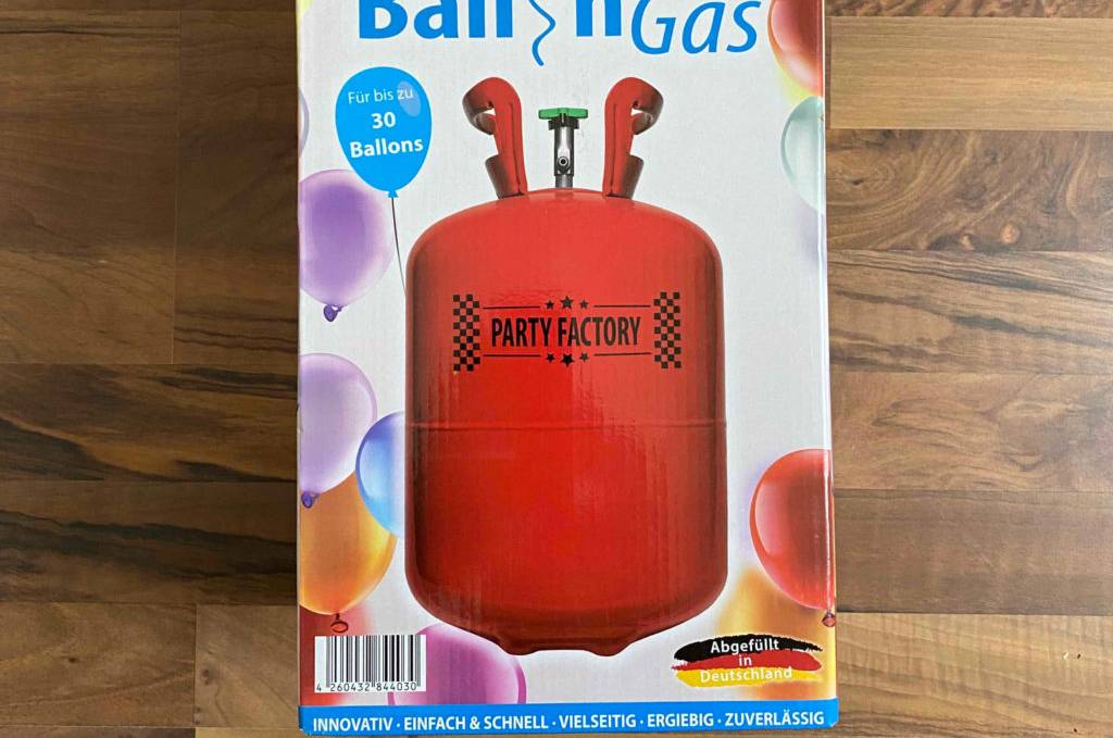 Eine getestetes Ballongas in Originalverpackung auf einem Holzboden liegend.