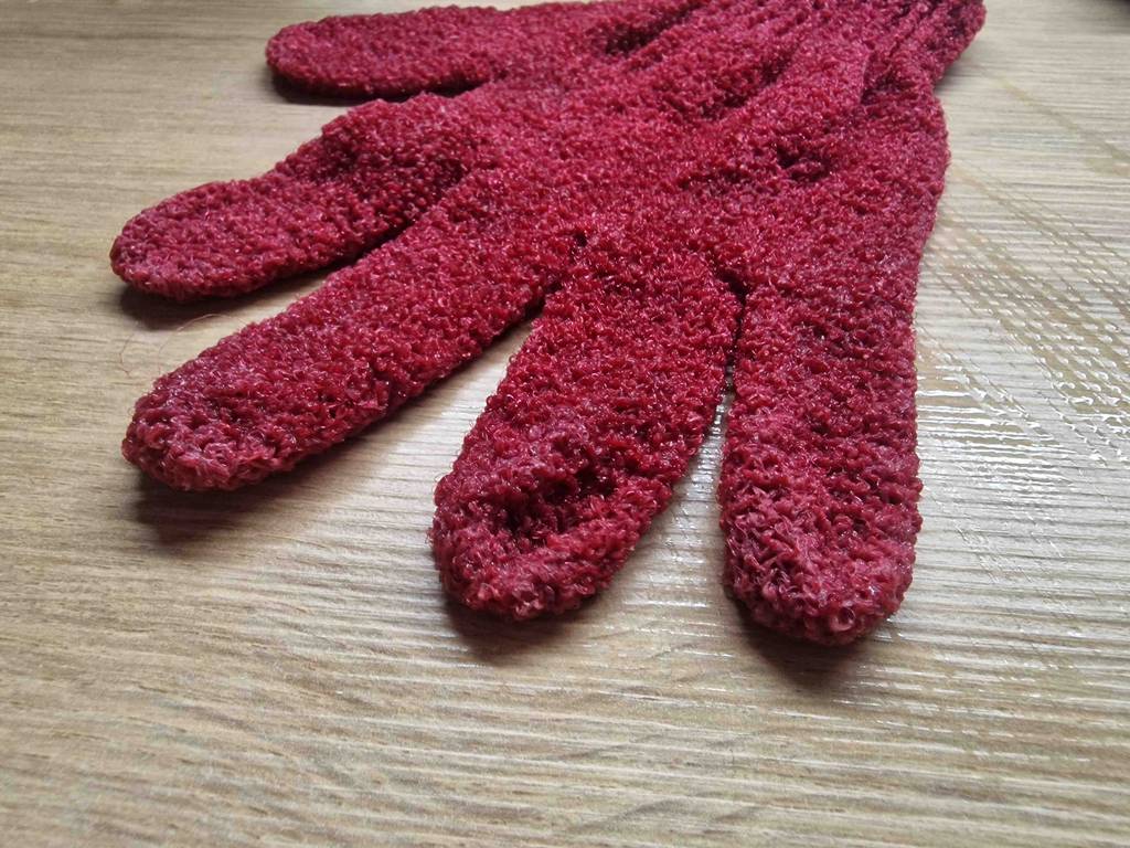 Peelinghandschuh-Test: roter Peelinghandschuh auf einer Holzfläche liegend.