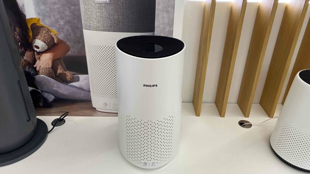 Ein getesteter Philips-Luftreiniger steht auf einem hellen Board neben anderen Produkten.