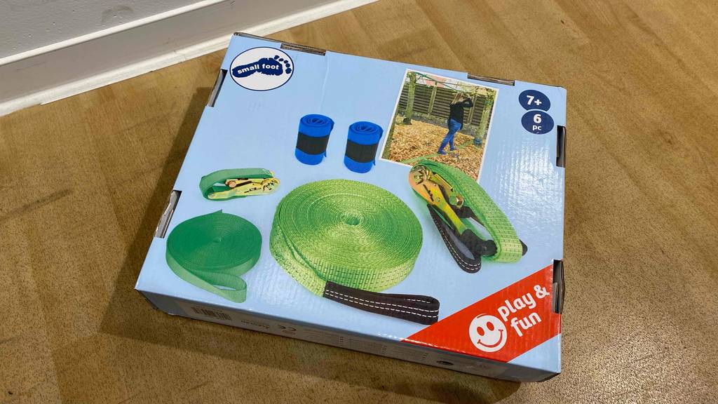 Auf einem Holzboden liegt eine getestete Slackline in Originalverpackung.