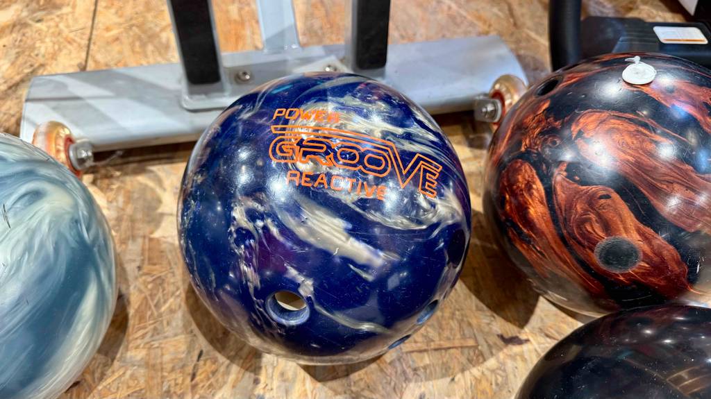 Mehrere getestete Bowlingkugeln liegen nebeneinander auf einer Holzfläche.