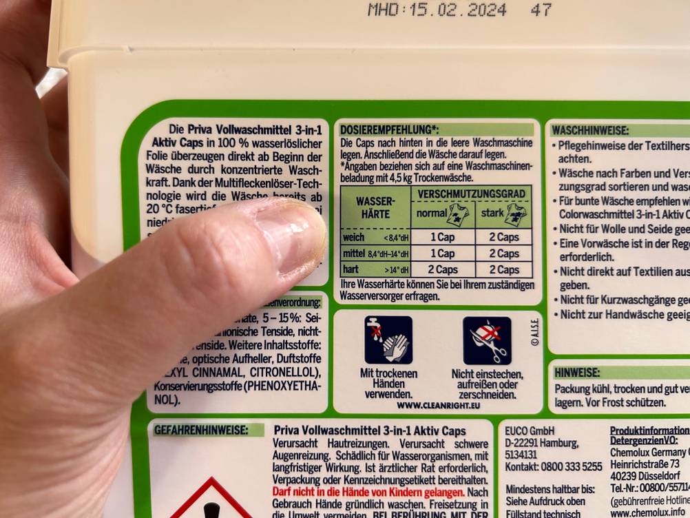 Ein Finger zeigt in Nahaufnahme auf die Rückseite der getesteten Waschmittel-Pods.