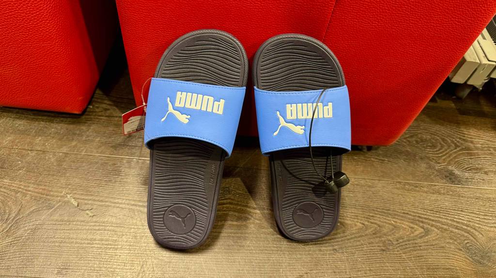 Badeschuhe im Test: Ein Paar Badeschuhe von Puma lehnen an einem roten Gegenstand.