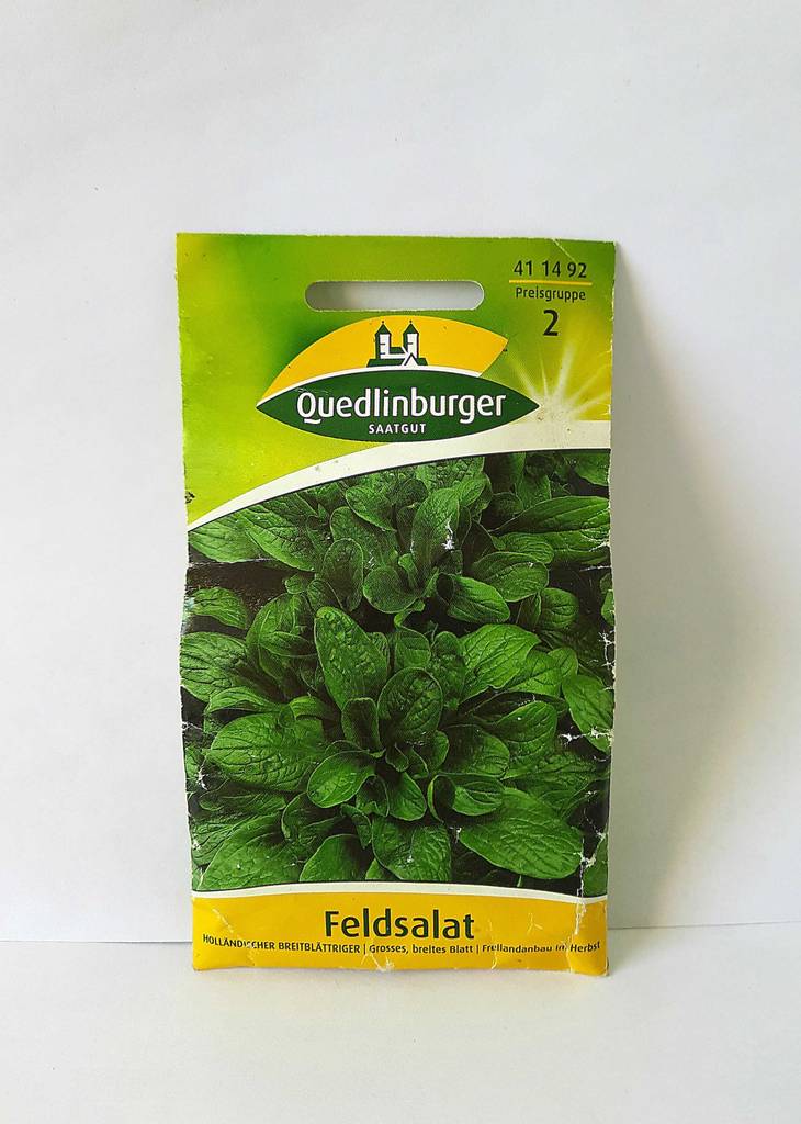 Die Verpackung der getesteten Feldsalat-Samen von vorn auf einer weißen Fläche liegend.
