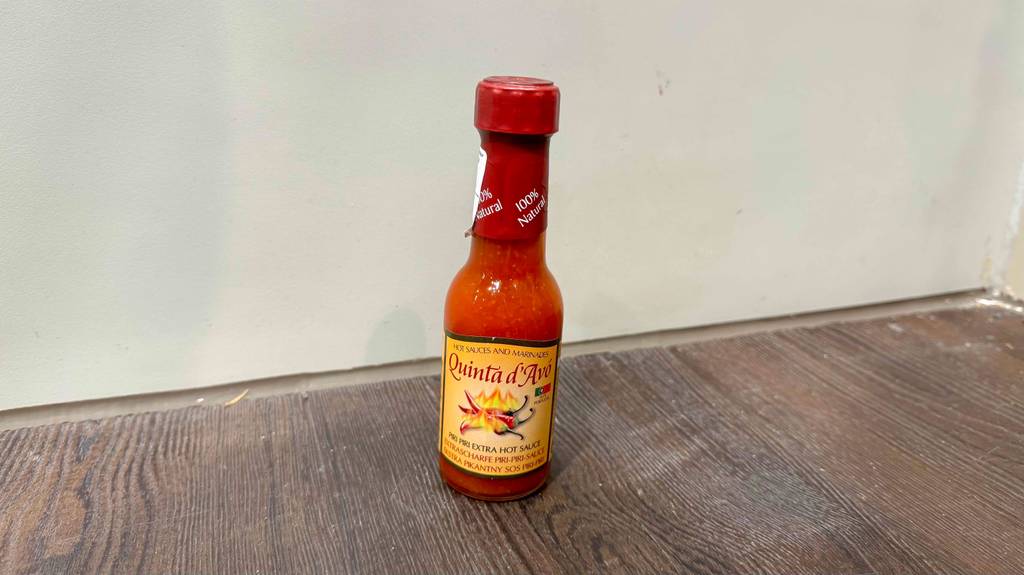 Eine Flasche scharfe Sauce steht vor einer Wand, die getestete wurde.