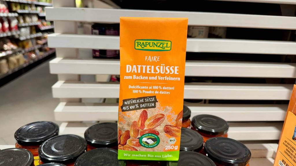 Dattelzucker im Test: Die orangefarbene Verpackung steht auf mehreren Schraubgläsern in einem Supermarkt.