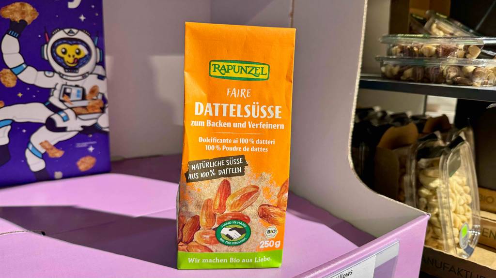 Der getestete Dattelzucker in der orangefarbenen 250-g-Verpackung steht auf einem lilafarbenen Karton im Supermarkt.