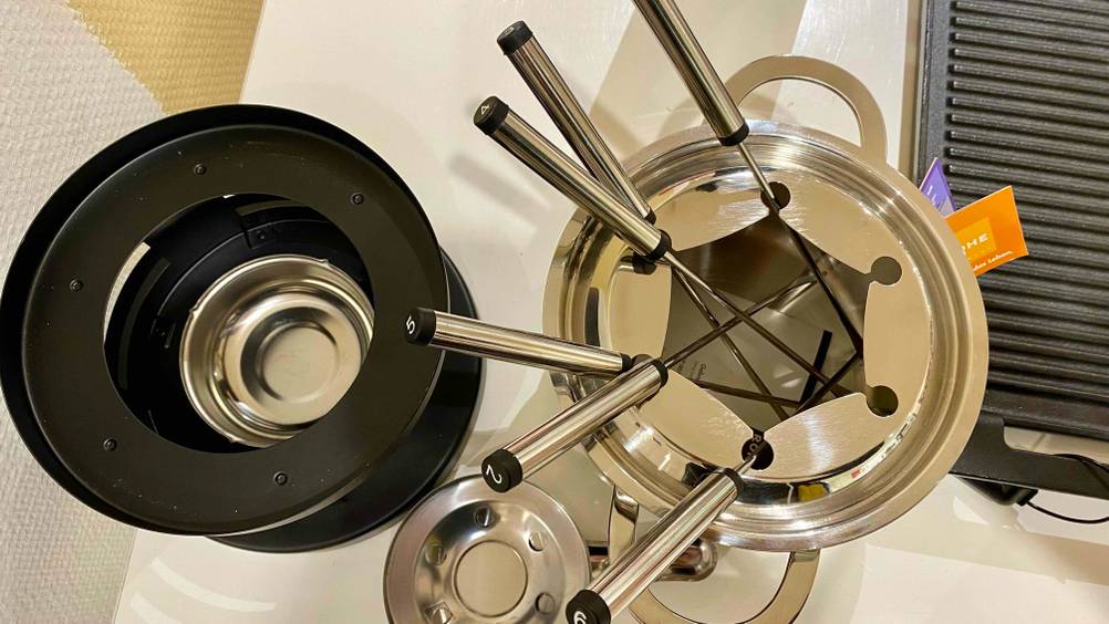 Fondue getestet: Ein Produkt neben seinem Stöfchen von oben auf einer hellen Fläche.